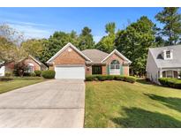 Charming brick home featuring a manicured lawn, arched window, and attached two-car garage at 1152 Strath Clyde Way, Mcdonough, GA 30253