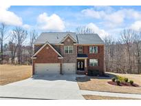 Inviting brick two-story home with an attached two-car garage, manicured lawn, and lush landscaping at 3316 Quarter Horse Ln, Conyers, GA 30013