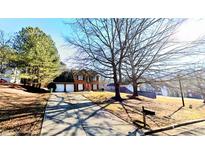 Charming two-story brick home with a well-manicured lawn, three-car garage, and a welcoming red front door at 3897 Vine Stone Dr, Stonecrest, GA 30038