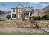 Charming two-story home with brick accents, a stone retaining wall, and a well-manicured lawn at 525 Village Arbor Park, Suwanee, GA 30024