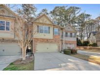 Charming townhome featuring a stone facade, a two-car garage, and beautiful landscaping at 145 Sunset Ln, Woodstock, GA 30189