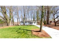 Charming single-story home with a well-manicured lawn and a long concrete driveway surrounded by mature trees at 618 Farrar Ct, Decatur, GA 30032