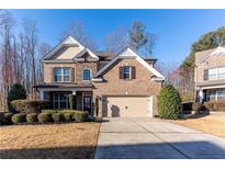 Charming brick two-story home with a well-manicured front yard and attached two car garage at 2035 Davallia Ct, Cumming, GA 30041