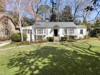 Charming single-story home featuring a lush green lawn, mature trees, and classic architectural details at 1015 Peachtree Battle Cir, Atlanta, GA 30327