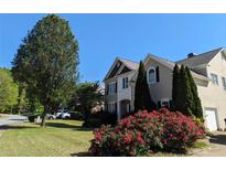 Charming two-story home with lush front lawn, mature tree, and vibrant flowering bushes on a sunny day at 1919 Barrett Knoll Nw Cir, Kennesaw, GA 30152