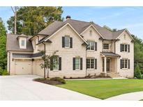 Charming two-story brick home with black shutters, a manicured lawn, and a three car attached garage at 4827 Basingstoke Dr, Suwanee, GA 30024