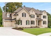 Charming two-story brick home with black shutters, lush lawn, and an attached two-car garage at 4827 Basingstoke Dr, Suwanee, GA 30024