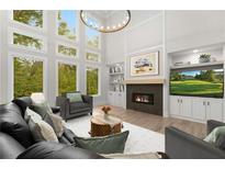 Stunning living room featuring soaring ceilings, a fireplace, and expansive windows with picturesque views at 4827 Basingstoke Dr, Suwanee, GA 30024