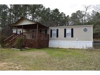 Charming home featuring a covered porch, wood stairs, and neutral siding, nestled among tall trees at 59 Pine Ridge Ln, White, GA 30184