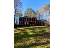 Charming brick home with a lush lawn, surrounded by mature trees on a sunny day at 1095 Willow Bnd, Roswell, GA 30075