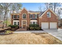 Charming two-story brick home with a well-manicured lawn, trimmed bushes, and a two-car garage, complemented by mature trees at 1904 Rosewood Ln, Woodstock, GA 30189