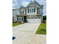 Charming two-story home featuring a symmetrical facade, double garage and well-manicured lawn at 11837 Rizvan Pl, Covington, GA 30014
