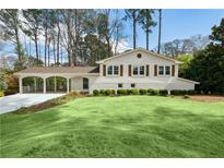 Charming home with pristine lawn, porte-cochere and a freshly painted white brick facade at 2133 Allaire Ne Ln, Decatur, GA 30345