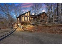 Unique two-story home with wood siding, special windows, and a charming fenced yard surrounded by mature trees at 804 Allatoona Crst, Woodstock, GA 30189