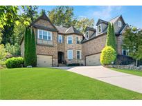 Charming two-story brick home with a well-manicured lawn, two-car garage, and mature trees at 4467 Sterling Pointe Nw Dr, Kennesaw, GA 30152