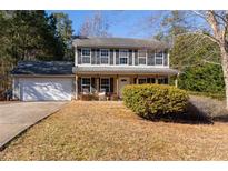 Traditional two-story home featuring a covered front porch, attached garage, and well-maintained landscaping at 25 Shadowbrook Ct, Covington, GA 30014