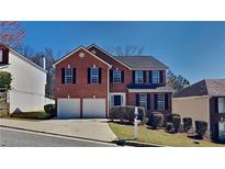 Charming two-story brick home featuring a two-car garage, black shutters, and a well-maintained lawn at 2431 Tolliver Dr, Ellenwood, GA 30294