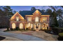 Elegant brick home boasts manicured landscaping, arched windows and stately presence with a circular driveway at 2250 Blackheath Trce, Alpharetta, GA 30005
