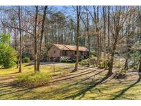 Charming brown home nestled among trees with landscaped yard and a driveway leading to the attached garage at 360 W Spalding Dr, Atlanta, GA 30328