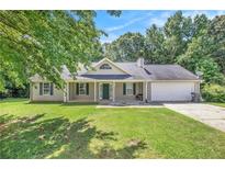Charming single-story home featuring a well-manicured lawn, inviting front porch, and attached two-car garage at 60 Cypress Dr, Covington, GA 30016