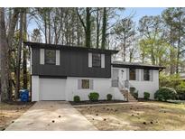 Charming two-story home with black and white painted brick, attached garage, and landscaped yard at 6710 Hidden Brook Trl, Atlanta, GA 30349