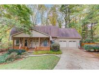 Charming single-Gathering home features a stone facade, a welcoming front porch, and a well-maintained lawn at 1667 Manhasset Farm Ct, Atlanta, GA 30338