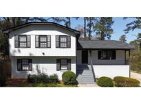 Inviting two-story home featuring a painted brick base, black shutters, and a charming covered front porch at 4087 Signal Rdg, Lilburn, GA 30047