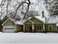 Charming home exterior with a well-manicured lawn and covered porch, complete with an attached garage at 10390 Rivertown Rd, Chattahoochee Hills, GA 30213
