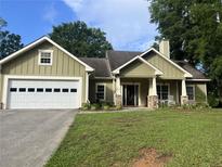 Charming one-story home featuring green siding, stone accents, and a well-manicured front lawn at 10390 Rivertown Rd, Fairburn, GA 30213
