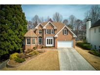 Charming two-story brick home featuring a well-manicured lawn and an attached two-car garage at 4089 Hooch River Trl, Suwanee, GA 30024