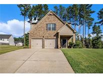 Charming brick home with a two-car garage, manicured lawn, and mature trees, offering classic curb appeal at 71 Pulaski Ave, Hampton, GA 30228