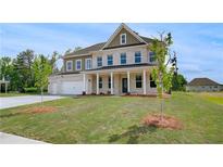 Beautiful two-story home with a well-manicured lawn, attached garage, and classic architectural details at 165 Haverling Pass, Hampton, GA 30228