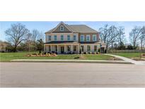 Charming two-story home with a covered porch and manicured lawn on a sunny day at 165 Haverling Pass, Hampton, GA 30228