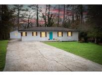 Charming brick home featuring a long driveway, manicured lawn, and vibrant blue door at 3893 Bonnie Se Ln, Atlanta, GA 30354