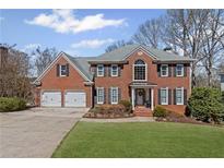 Stately brick home featuring a two-car garage, manicured lawn, and classic architectural details at 3858 Fenway Xing, Marietta, GA 30062