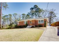 Charming brick ranch home featuring a well-manicured lawn and long driveway at 247 Heaton Park Dr, Atlanta, GA 30030