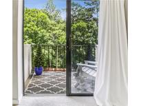 View of a cozy balcony with outdoor seating, patterned rug, and lush green trees in the background at 300 Johnson Ferry Ne Rd # A313, Atlanta, GA 30328