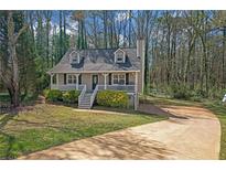 Charming home with a front porch, landscaped yard, and a driveway, enveloped by mature trees providing natural shade at 4382 Conwhey Sw Ct, Smyrna, GA 30082