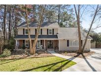 Charming two-story home featuring traditional architecture, lush landscaping, and a welcoming front porch with sitting area at 3413 Dunwoody Club Dr, Atlanta, GA 30350