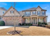 Charming two-story home featuring a brick and tan exterior with a well-manicured lawn at 257 Lakestone Pkwy, Woodstock, GA 30188