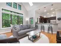 Bright living room boasts a large window, hardwood floors, a gray sofa and access to kitchen with breakfast bar at 1903 Anjaco Rd # 5, Atlanta, GA 30309
