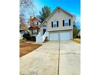 Charming two-story home features a two-car garage, light beige siding, and a welcoming front entrance with a white staircase at 4435 Grove Nw Dr, Acworth, GA 30101