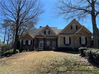 Charming home featuring stone and siding, complemented by manicured landscaping and mature trees on a sunny day at 627 Warsaw Rd, Roswell, GA 30075