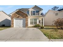 Charming two-story home featuring stone accents, attached garage, and well-maintained lawn at 6439 Grey Fox Way, Riverdale, GA 30296