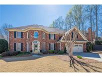 Charming brick home features a manicured lawn, attached two-car garage, and beautiful, mature landscaping at 6820 Olde Atlanta Pkwy, Suwanee, GA 30024
