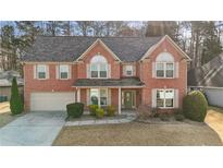 Charming two-story brick home with a well-manicured lawn, attached garage, and inviting front porch at 675 Timber Ives Dr, Dacula, GA 30019