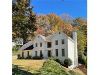 Beautiful two-story white home with a black door, complemented by the vibrant colors of fall foliage at 2115 Azalea Dr, Roswell, GA 30075
