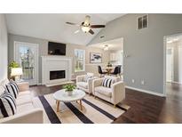 Bright living room featuring a fireplace, neutral walls, ceiling fan and dark hardwood floors at 1542 Bogota Way, Jonesboro, GA 30236