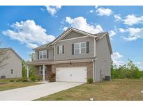 Two-story home boasts a lush lawn, long driveway, and attached garage with a beautiful blue sky at 4825 Layton Drive, Lithia Springs, GA 30122