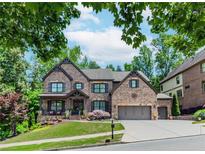 Stunning brick two-story home with a manicured lawn and a three-car garage at 1351 Ashbury Park Dr, Hoschton, GA 30548